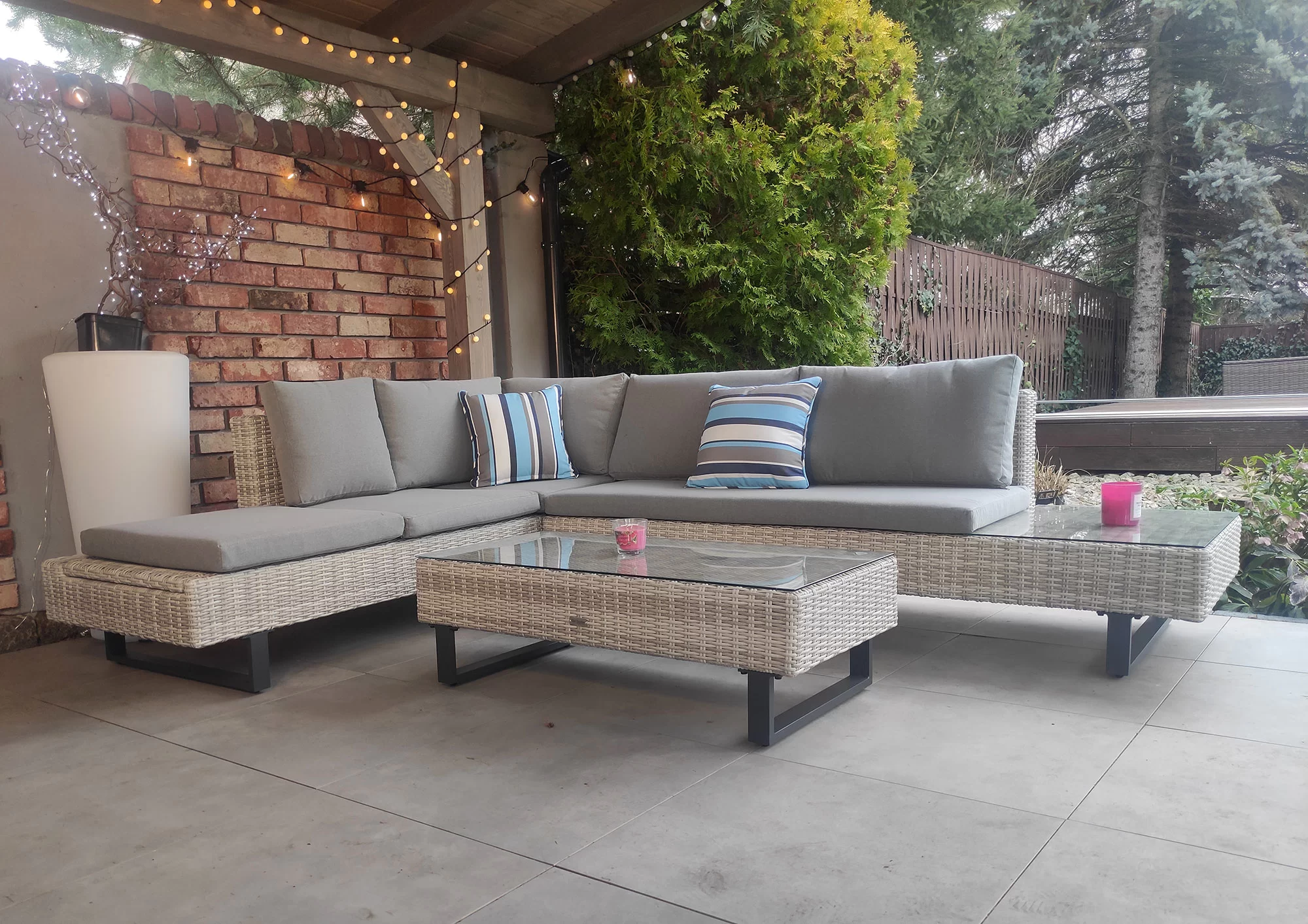 Narożnik PINETO jasno-szary pod pergolą — kąt 3/4 z ceglaną ścianą